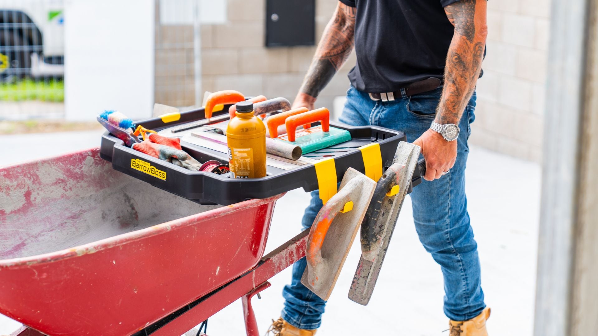 Barrow Boss wheelbarrow workstation attachment carrying tools and equipment on a construction site.
