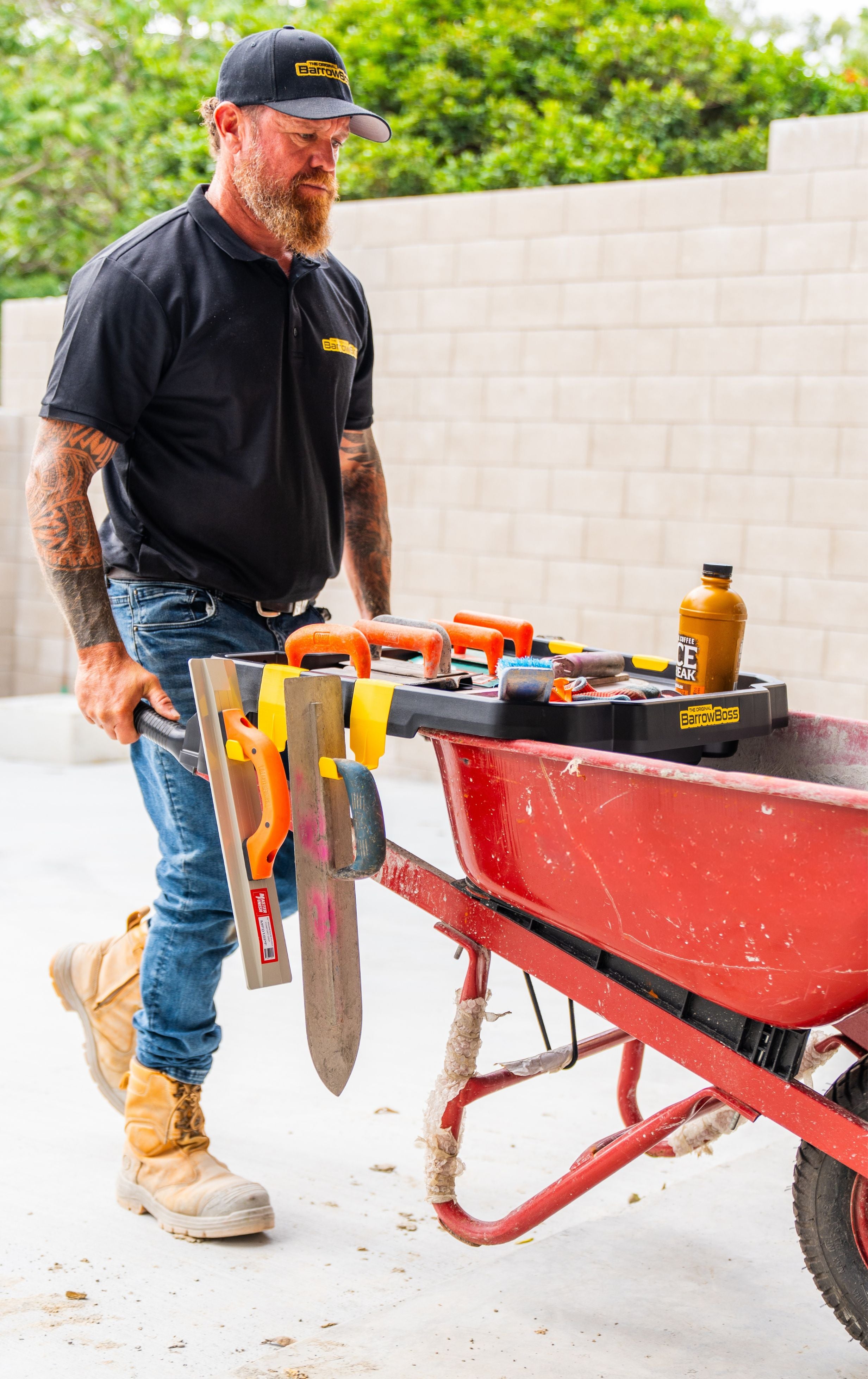 Tradie using the Barrow Boss wheelbarrow workstation attachment on a construction site.
