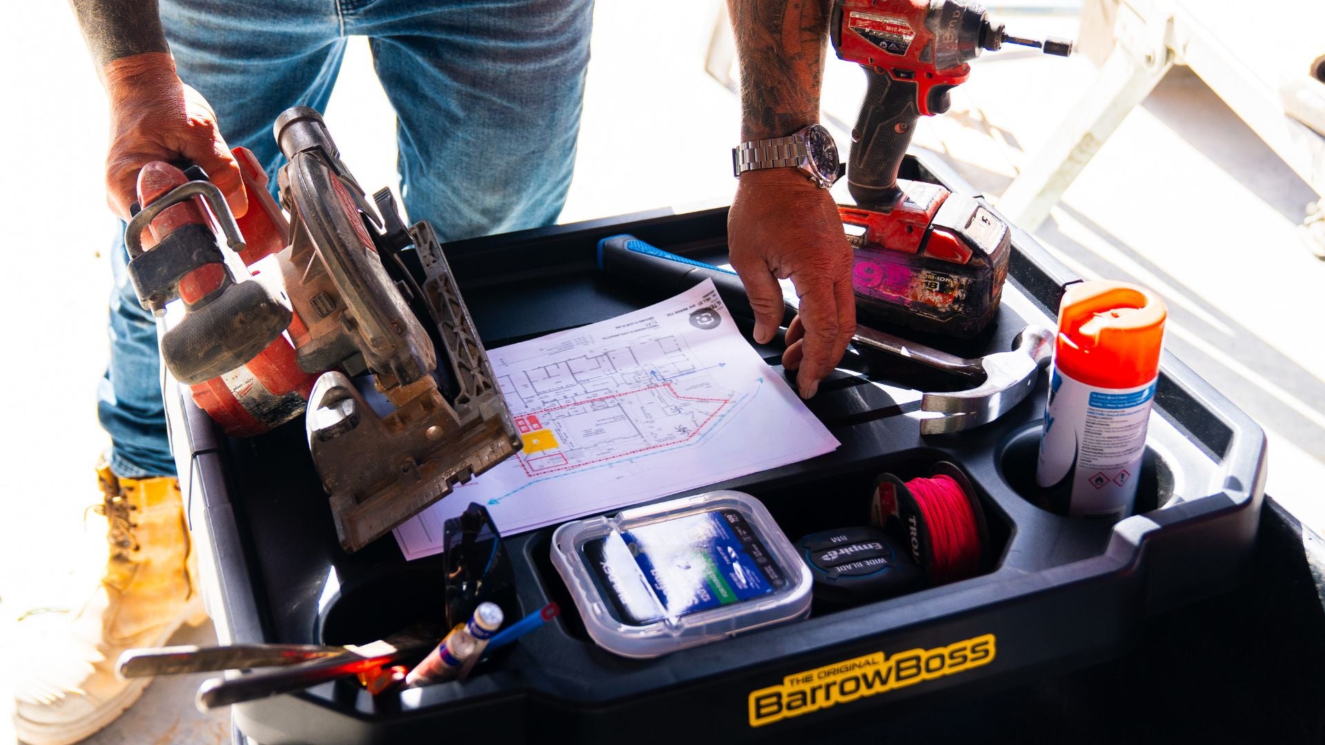 Barrow Boss wheelbarrow workstation holding power tools, site plans, tape measure and trade supplies on a construction site.

